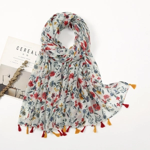 Close-up of lightweight floral scarf featuring delicate red and yellow tassels on white