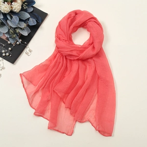 Detailansicht eines korallenrosa Chiffon-Strandtuchs mit weicher Textur und Saum