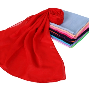 Vibrant red chiffon scarf for women with stack of colorful scarves in background
