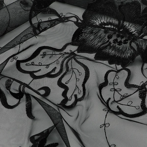 Vue macro du tissu en maille noire élégante avec broderie florale sur l'écharpe triangle