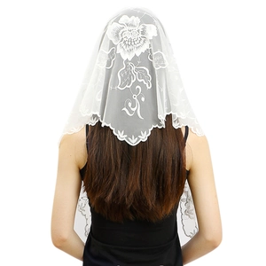 Détail de la broderie florale blanche et bordure en dentelle sur un voile de mariée léger
