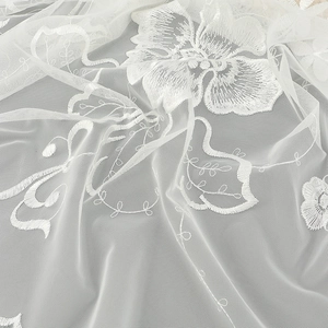 Détail de la broderie florale blanche sur un tissu en dentelle de maille transparent