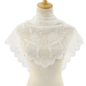 Close-up of white lace bridal shawl featuring floral embroidery and scalloped edges