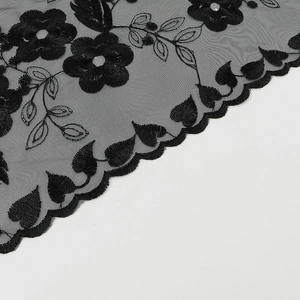 Détail de dentelle à broderie florale noire avec maille et bords festonnés