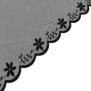 Close-up of black embroidered lace fabric with delicate floral patterns and scalloped edges