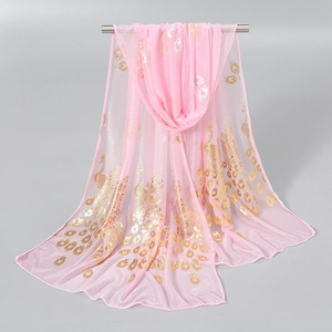 Detail of pink chiffon scarf with elegant gold peacock feather print draped on metal rod