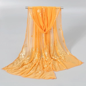 Detailed close-up of orange translucent scarf with elegant gold peacock feather print