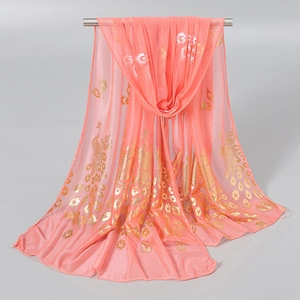 Detail of coral pink scarf with golden peacock feather print and shimmering texture