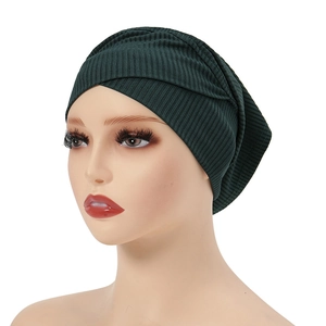 Detail of dark green ribbed knit turban featuring a stylish front cross knot design