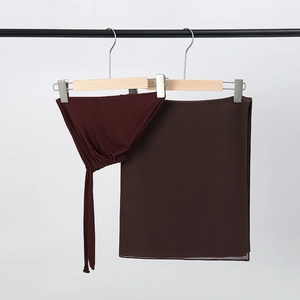 Detail view of burgundy chiffon hijab and matching inner cap hanging on a clothes rack