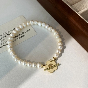 Vue détaillée d'un bracelet en perles d'eau douce fait main avec fermoir fleur dorée