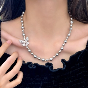 Collier en perles grises avec pendentif papillon étincelant porté par un mannequin