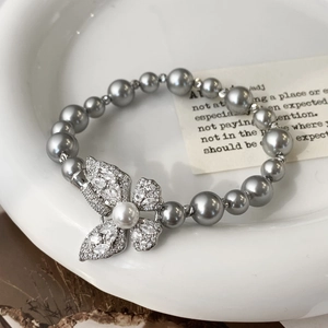 Gros plan d'un bracelet en perles élégant avec charm papillon brillant sur plateau céramique