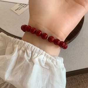 Bracciale vintage in perle di agata rossa con dettaglio dorato sul polso di un modello