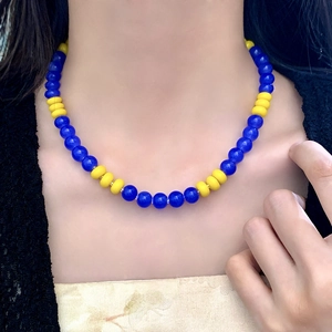 Minimalist necklace with deep blue glass beads and yellow flat beads worn on collarbone
