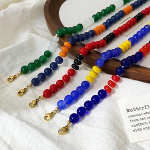 Colorful beaded stainless steel necklaces with gold lobster clasps on a wooden tray