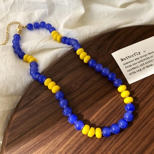 Detailed shot of dark blue and yellow glass bead necklace with golden lobster clasp