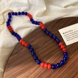 Detail of colorful glass bead necklace with gold lobster clasp on a rustic wood tray