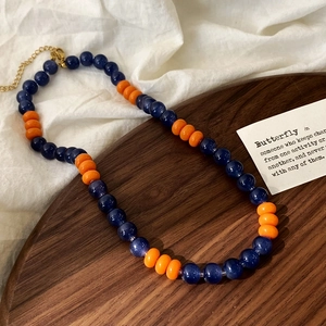 Close-up of blue and orange glass beads necklace with golden lobster clasp detail