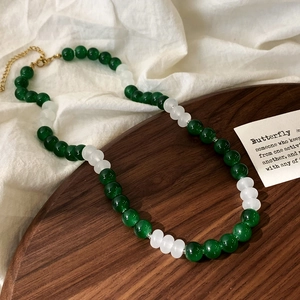Detail of green and white glass bead necklace with golden lobster clasp and chain