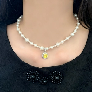 Gros plan d'un collier de perles avec un pendentif en pierre jaune pierre précieuse carrée