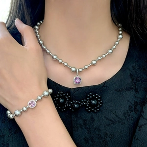 Détail de bijoux en perles grises avec pierres précieuses violettes et cristaux fins