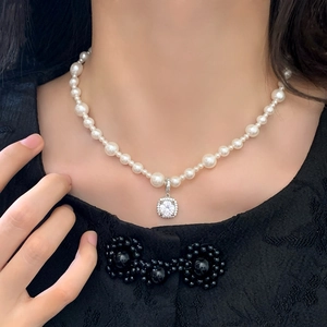 Gros plan d'un collier de perles avec pendentif carré en zircon porté par un mannequin