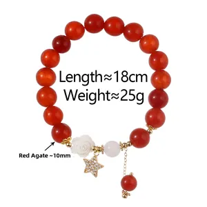 Detail eines roten Achatperlenarmbands mit weißer Kamelie und goldenem Sternanhänger