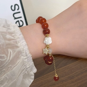 Vintage Armband aus roten Achatperlen mit Kamelienblüte und Sternanhänger am Handgelenk