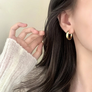Élégantes boucles d'oreilles créoles double couche plaquées or 18 carats sur un modèle