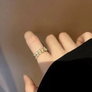 Elegant gold-tone leaf-shaped open ring with cubic zirconia on a female finger
