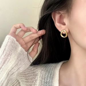 Minimalist geometric gold-plated twisted hoop earrings worn by a model in a warm setting