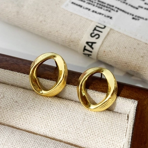 Macro detail of gold irregular oval earrings with twisted geometric vertical textures