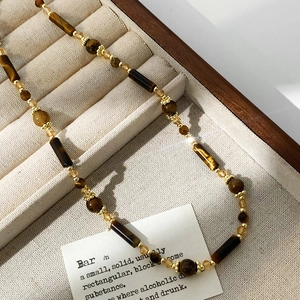 Collana di perle occhio di tigre vintage con accenti dorati su espositore