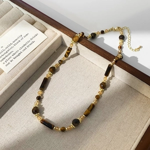 Dettaglio macro della collana in occhio di tigre con perle dorate in una scatola portagioie