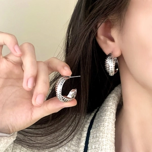 Orecchini a cerchio larghi in argento con scanalature orizzontali indossati da modella