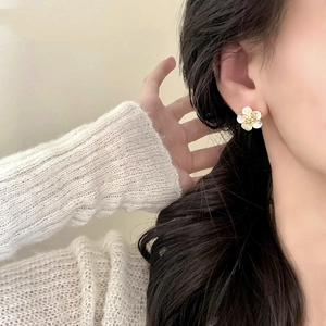 Elegant gold flower stud earrings with pearl petals and zircon center on model