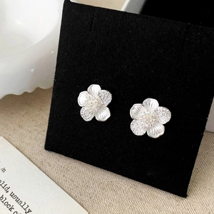 Close-up of elegant flower earrings with white shell petals and shimmering cubic zirconia