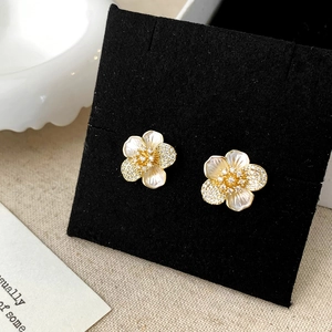 Detailed view of elegant gold flower earrings with white shell petals and zircons