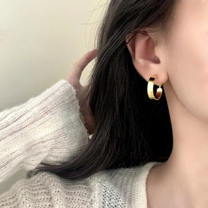Polished gold circular hoop earrings on female model in natural lighting minimalist style