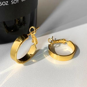 Macro shot of minimalist gold plated C-shape earrings with polished mirror finish