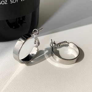 Close-up of shiny silver wide hoop earrings with a polished metallic finish and buckle