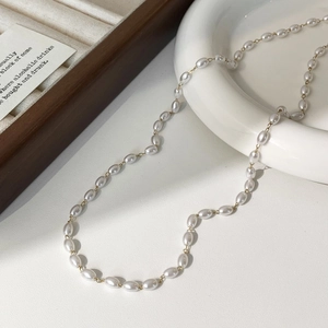 Detail einer eleganten Perlenkette mit Goldkette auf Keramik und Holzschmuckschale