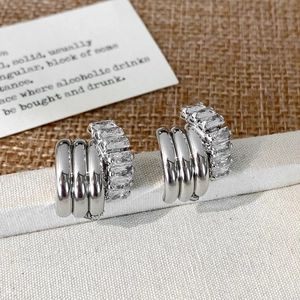 Detail of silver C-shaped multi-layer earrings with baguette-cut zircon stones