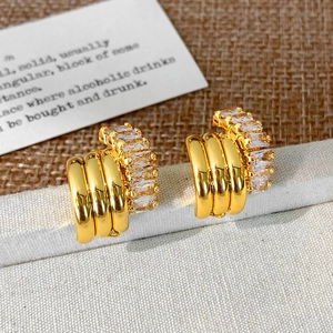 Detail of C-shaped gold-plated earrings featuring rectangular cubic zirconia settings