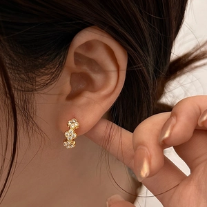 Gros plan sur les boucles d'oreilles trèfle à trois fleurs avec zircons étincelants