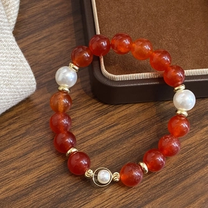 Retro red agate and pearl beaded bracelet with gold metal charms on a luxury gift box