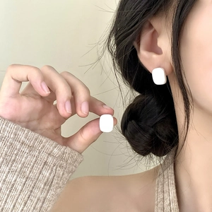 Boucles d'oreilles carrées blanches minimalistes avec finition lisse portées à l'oreille