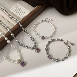 Gros plan sur pendentifs en pierres violettes sur collier et bracelet de perles élégantes