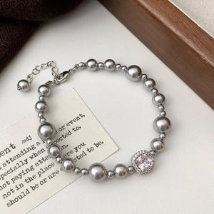 Détail d'un élégant bracelet en perles grises avec pendentif carré en zircone